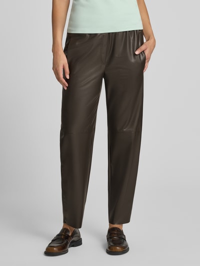 Frauenmodel trägt Tapered Fit Hose in Leder-Optik von Marc Cain, braun, verkürzte Passform, elastischer Bund, Eingrifftaschen, Ganzkörperansicht von vorne.