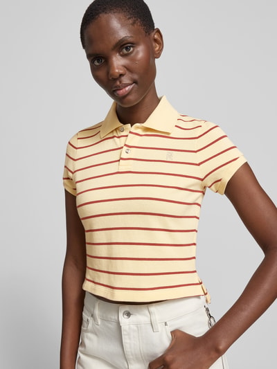 Frauenmodel trägt Cropped Poloshirt aus reiner Baumwolle von Rabanne in Gelb mit roten Streifen, Polokragen, kurzärmelig, Nahaufnahme Oberkörper.