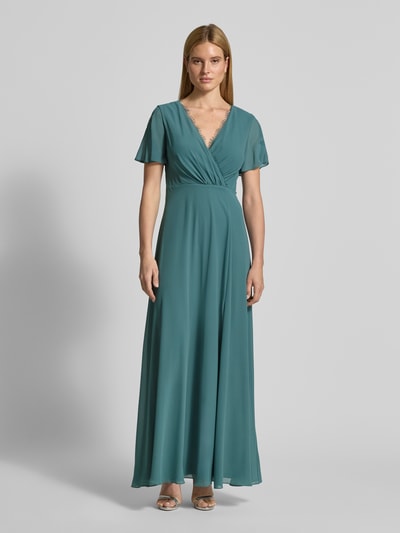 Frauenmodel trägt Damen Abendkleid mit Spitzenbesatz von Christian Berg Cocktail in Taillierter Passform, V-Ausschnitt, Wickel-Optik, semitransparentem, kurzärmeligem Design, in Petrol, fließender Stoff, Ganzkörperansicht von vorne.