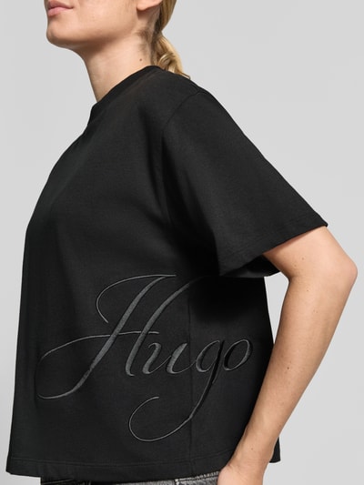 Vrouwenmodel draagt Loose Fit T-Shirt aus reiner Baumwolle Modell 'Duslant' van HUGO, zwart, grafisch logo, Dames t-shirt, zijaanzicht, Nahaufnahme Oberlichaam.