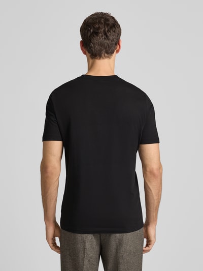 Männermodel trägt T-Shirt aus Baumwolle Modell 'Thompson' von BOSS in Schwarz, gerade Passform, dezenter Logo-Print, Ganzkörperansicht Rückansicht.