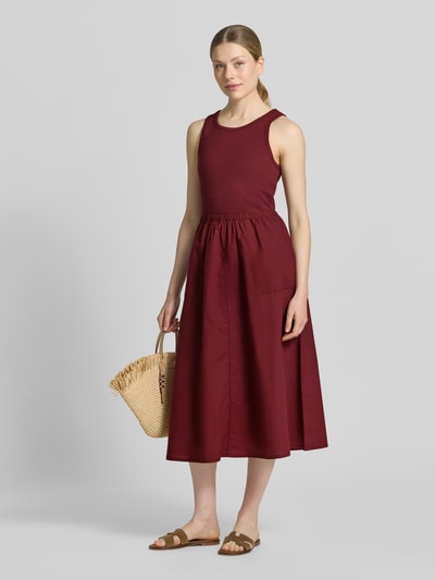 Frauenmodel trägt Fit and Flare Freizeitkleid aus reiner Baumwolle von s.Oliver RED LABEL in Dunkelrot, schlichte Struktur, Ganzkörperansicht von vorne.