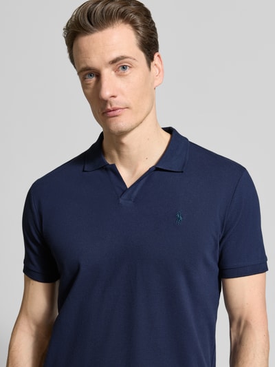 Männermodel trägt Slim Fit Poloshirt aus Baumwoll-Mix von Polo Ralph Lauren, unifarbenes Dunkelblau, Logo-Detail, Nahaufnahme Oberkörper.