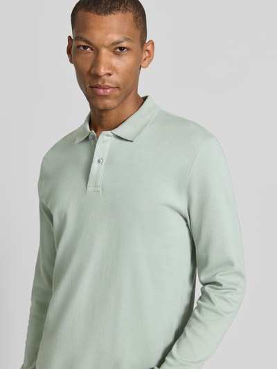 Männermodel trägt Regular Fit Poloshirt aus reiner Baumwolle von Christian Berg Men in Pastellgrün, langärmelig, Nahaufnahme Oberkörper.