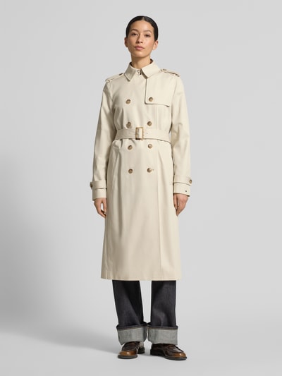 Vrouwenmodel draagt Slim Fit Trenchcoat aus reiner Baumwolle van Tommy Hilfiger in effen beige twill met dubbele knopen, riem en labeldetail, volledig lichaam vooraanzicht.
