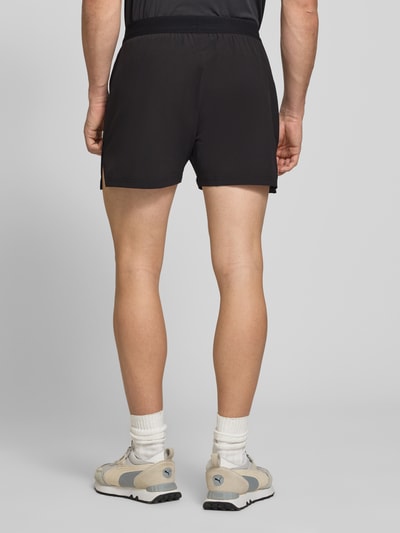 Männermodel trägt Regular Fit Shorts mit Logo-Print von PUMA PERFORMANCE in Schwarz, elastischer Bund, Eingrifftaschen, Ganzkörperansicht Rückansicht.