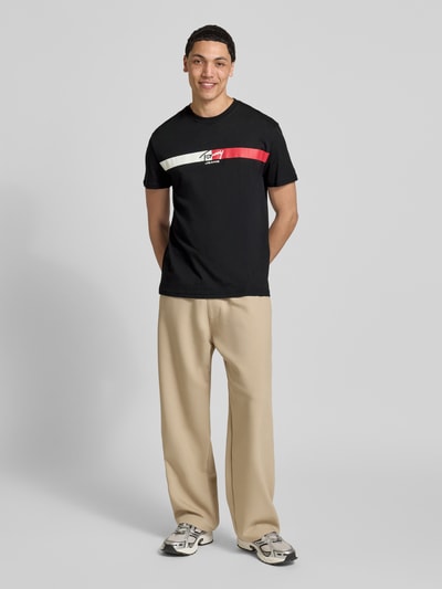 Männermodel trägt Regular Fit T-Shirt aus reiner Baumwolle von Tommy Jeans, Optik: Unifarben, Passform: Regular-Fit, Label-Print, Rundhals-Ausschnitt, Ärmelform: Kurzarm, Materialverarbeitung: Jersey, Material: Reine Baumwolle, Ganzkörperansicht von vorne.