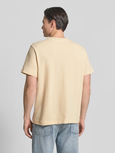 Männermodel trägt Regular Fit T-Shirt aus reiner Baumwolle Modell 'COOPER' von SELECTED HOMME in Beige mit Strukturmuster, Ganzkörperansicht Rückansicht.