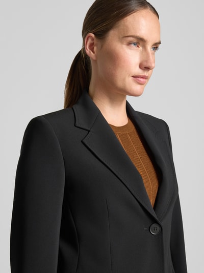 Frauenmodel trägt Slim Fit Longblazer mit Reverskragen Modell 'LINZ' von Max Mara Studio in Schwarz, strukturierte Oberfläche, Nahaufnahme Oberkörper.