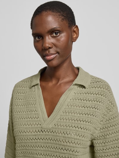 Modelka nosi Strickpullover mit V-Ausschnitt und 3/4-Arm Modell 'Garakino' od OPUS, bawełna, krój relaxed fit, polokragen, kolor jasna zieleń, tekstura dziana, dekolt w szpic, długość tyłu 56 cm, długość rękawa 33 cm; zbliżenie na górną część ciała