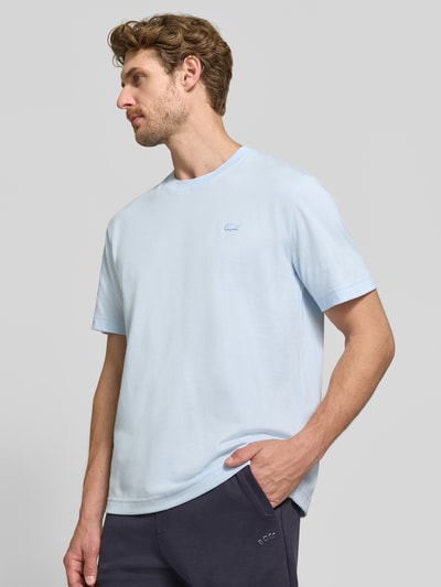 Męski model nosi Regular Fit T-Shirt aus reiner Baumwolle von Lacoste, jasnoniebieski kolor, gładka faktura, Ganzkörperansicht von vorne.