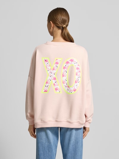Frauenmodel trägt Oversized Sweatshirt mit Pailettenbesatz Modell 'XO' von miss goodlife in Rosa, reine Baumwolle, Rückansicht Ganzkörperansicht.