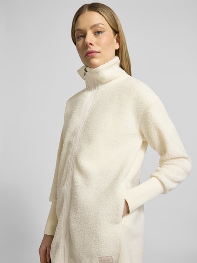 Frauenmodel trägt Fleecejacke mit Stehkragen Modell 'TOLA' von Didriksons in Creme, Relaxed-Fit, Reißverschluss, Nahaufnahme Oberkörper. Rückenlänge bei Größe 36: 83 cm, Schulterbreite: 52 cm, Brustweite: 47 cm, Ärmellänge: 56 cm. Textur weich und flauschig.
