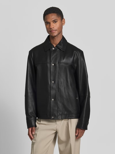Männermodel trägt Regular Fit Lederjacke Modell 'JOBAN' von BOSS Orange in schwarzer Lederoptik, Umlegekragen, Eingrifftaschen, Ganzkörperansicht von vorne.