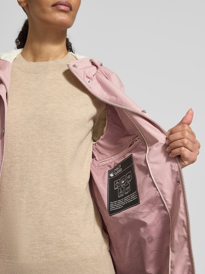 Frauenmodel trägt Jacke mit Ärmelriegeln von NAUTGÅRD in zartem Rosa mit Kapuze, Knopfleiste und Reißverschlusstaschen, Nahaufnahme Oberkörper