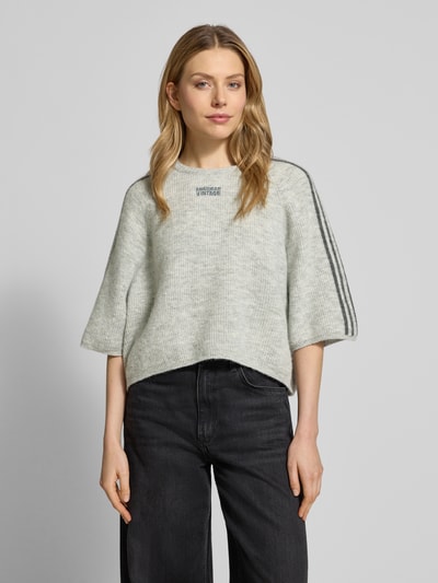 Vrouwenmodel draagt Cropped Strickpullover mit gerippten Abschlüssen Modell 'VITOW' van American Vintage, lichte kleur, los model, ronde hals, wollen-alpaca-mix met stretch, label-stitching, ribboorden, Ganzkörperansicht von vorne.
