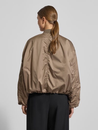Frauenmodel trägt Regular Fit Bomberjacke mit Stehkragen Modell 'Lorraine' von Guess, braun, elastische Abschlüsse, Eingrifftaschen, Rückenansicht.