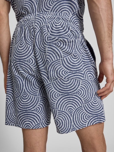Männermodel trägt Relaxed Fit Sweatshorts mit Baumwoll-Anteil Modell 'CLEMENT' von Only & Sons, blau-weißes Allover-Muster, Frottee, Ganzkörperansicht Rückansicht.