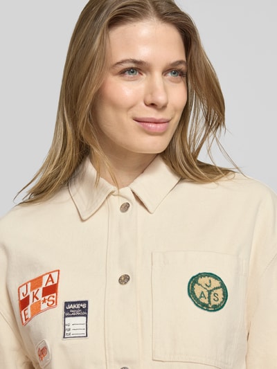 Frauenmodel trägt Regular Fit Hemdjacke mit Motiv-Patches von Jake*s Casual aus reiner Baumwolle, aufgesetzte Taschen, Umlegekragen, Knopfleiste, Nahaufnahme Oberkörper