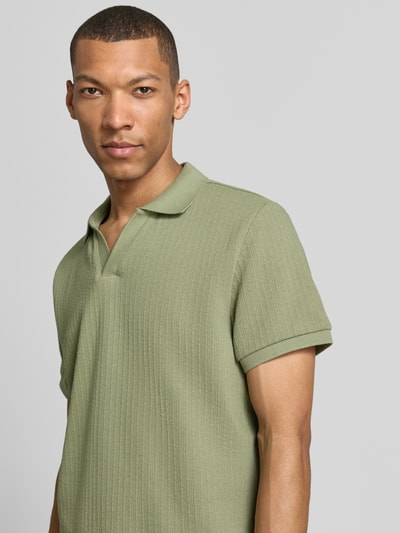 Męski model nosi Regular Fit Strick-Poloshirt mit V-Ausschnitt von MCNEAL, mieszanka bawełny z dodatkiem streczu, kolor jasna zieleń, krótki rękaw, dekolt w serek, tekstura prążkowana, długość tyłu w rozmiarze M: 70 cm, koszulka polo, zbliżenie na górną część ciała, ujęcie z przodu.