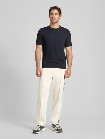 Männermodel trägt Sweatpants mit Label-Patch und elastischem Bund von ARMANI EXCHANGE aus Baumwoll-Mix mit Stretch-Anteil, Relaxed-Fit, Längsnähte, cremefarben, Innenbeinlänge 42 cm in Größe M, Ganzkörperansicht von vorne