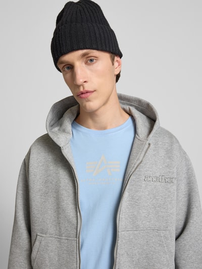 Männermodel trägt T-Shirt mit Logo und Rundhalsausschnitt von Alpha Industries aus Reine Baumwolle im Regular-Fit, Nahaufnahme Oberkörper.