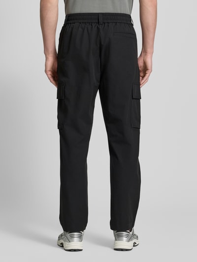 Männermodel trägt Relaxed Fit Cargohose mit Gürtelschlaufen Modell 'SRACKY' von BOSS Orange, Optik: Unifarben, Passform: Relaxed-Fit, Label-Patch, seitliche Eingrifftaschen, Gesäßtaschen, Cargotaschen, Ganzkörperansicht Rückansicht.