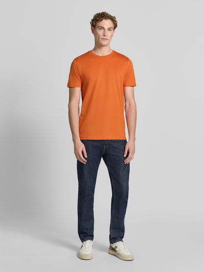 Męski model nosi T-Shirt aus Baumwolle mit Rundhalsausschnitt von Christian Berg Men, krój slim fit, okrągły dekolt, długość tyłu 73 cm, pomarańczowy, całopostaciowy widok z przodu.