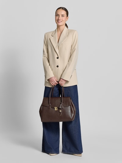 Frauenmodel trägt Handtasche mit Tragehenkeln Modell 'SIENA' von Mango in Braun mit Überschlag, Klickverschluss, Ganzkörperansicht von vorne. Breite bei Größe 1: 38 cm, Länge: 31 cm, Tiefe: 18 cm, Hauptfach, Innenfach mit Reißverschluss, Länge Schulterriemen: 66 cm.
