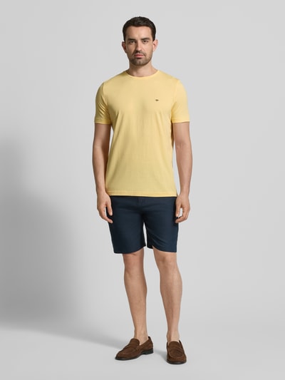 Męskamodel nosi T-Shirt mit Rundhalsausschnitt und Label-Stitching od Fynch-Hatton w kolorze jasnożółtym, czysta bawełna, krój regular fit, długość tyłu w rozmiarze M: 71 cm, widok całej sylwetki z przodu.
