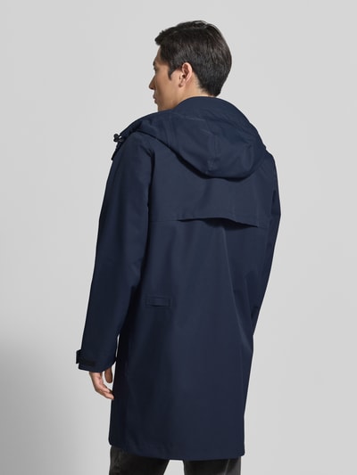 Männermodel trägt dunkelblaue Regenjacke mit Kapuze, Kordelzug und Reißverschlusstaschen Modell 'RAIN EATER' von GOFRANCK, Ganzkörperansicht Rückansicht.