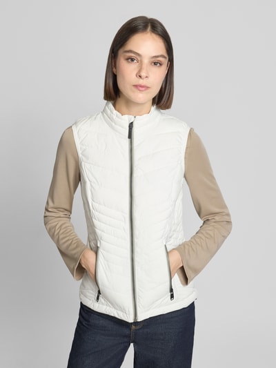 Vrouwenmodel draagt witte bodywarmer met opstaande kraag, ritssluiting, ritszakken, model 'GS109' van g.i.g.a. dx, slim fit, waterdicht tot 10.000 mm, ruglengte maat 36: 61 cm, schouderbreedte: 37 cm, borstwijdte: 49 cm, vooraanzicht bovenlichaam