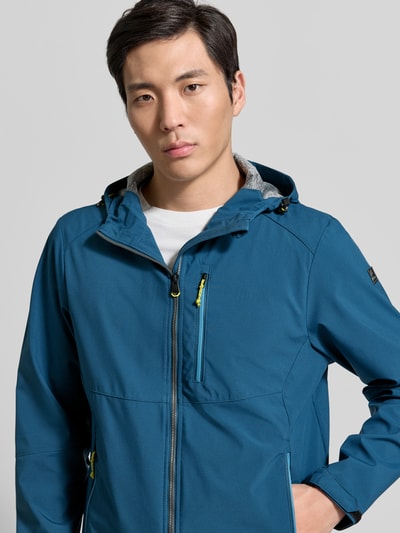 Männermodel trägt Regular Fit Jacke mit Logo-Applikation von Killtec in Blau mit Kapuze, Napoleontasche, Reißverschlüssen, Nahaufnahme Oberkörper.