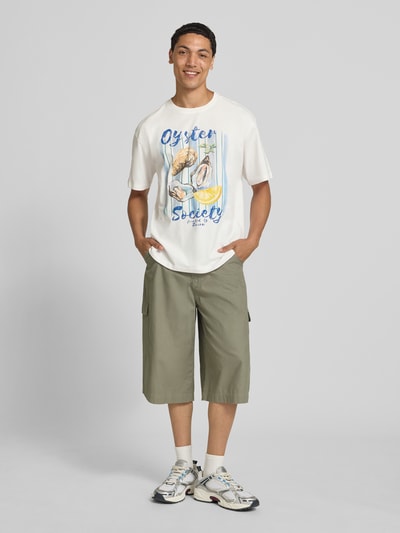 Männermodel trägt T-Shirt mit Motiv-Print von REVIEW aus Baumwoll-Mix mit Bio-Baumwoll-Anteil, Gerader-Schnitt, Rundhalsausschnitt, Ganzkörperansicht von vorne.