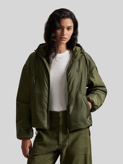 Modelka nosi Relaxed Fit Blouson mit Zweiwege-Reißverschluss od Polo Ralph Lauren, jednolity khaki, kaptur z tunelem, balonowe rękawy, elastyczne wykończenia, boczne kieszenie, logo na piersi, widok całej sylwetki z przodu.