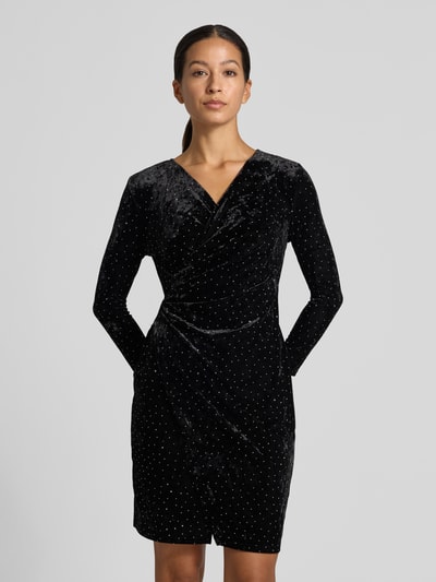 Vrouwenmodel draagt Samtkleid in Minilänge mit Stretch-Anteil van Apricot, zwart met All-over strass-steentjes, V-hals, wikkellook, getailleerd, plooien, elastische materiaalmix, met lange mouwen, minilengte, ruglengte maat S 89 cm, borstwijdte 35 cm, mouwlengte 65 cm, nahaufnahme bovenlichaam