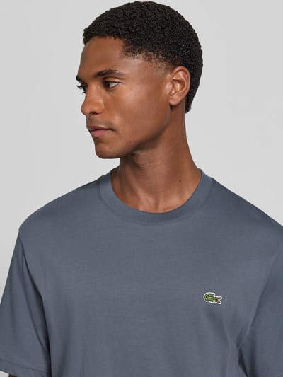 Männermodel trägt Regular Fit T-Shirt aus reiner Baumwolle von Lacoste in Dunkelblau mit glatter Textur, Nahaufnahme Oberkörper, Herren T-Shirt von Lacoste.