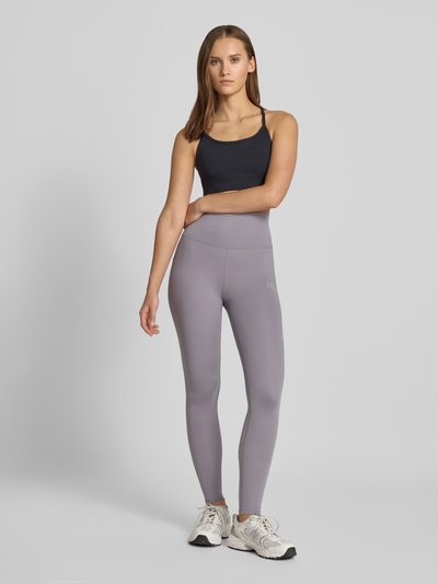 Frauenmodel trägt Slim Fit Leggings mit Logo-Print Modell 'Harmony' von New Balance in Hellgrau, elastischer Bund, Jersey, Ganzkörperansicht von vorne.