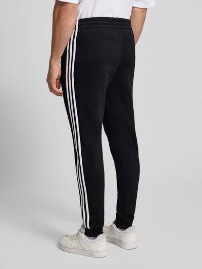 Männermodel trägt Sweatpants mit elastischem Bund von adidas Originals, Material-Mix mit Stretch-Anteil, Label-Stitching, Ganzkörperansicht Rückansicht.