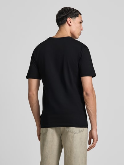 Männermodel trägt T-Shirt mit Label-Stitching Modell 'CASSICA' von Ellesse, Schwarz, Reine Baumwolle, Gerader-Schnitt, Rückenansicht, Ganzkörperansicht Rückansicht.
