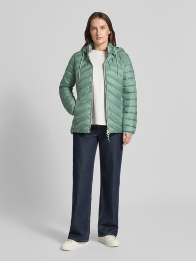 Frauenmodel trägt Regular Fit Steppjacke mit abnehmbarer Kapuze von s.Oliver RED LABEL in Hellgrün, unifarben, Ganzkörperansicht von vorne.