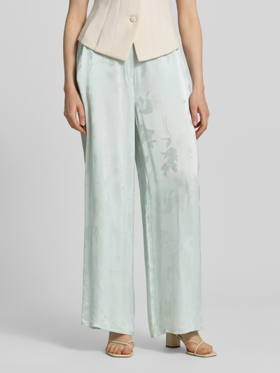 Frauenmodel trägt Weite Hose aus reiner Viskose von Calvin Klein Womenswear in Hellgrün mit Allover-Jacquardmuster, seitliche Taschen, Nahaufnahme Unterkörper.