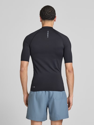 Mannenmodel draagt Sonnenschutz Wet Shirt Surfshirt met UPF50 Modell 'EVERYDAY' van Quiksilver, zwarte elastische stof, aansluitende fit, opstaande kraag, korte mouw, labelprint, productdetails uit context, volledige achterkantaanzicht.