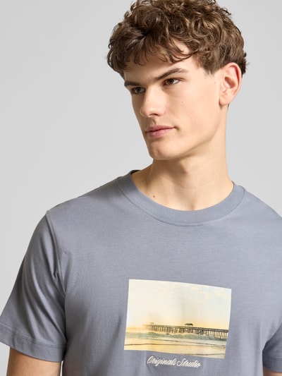 Männermodel trägt T-Shirt mit Rundhalsausschnitt Modell 'JORNORREBRO' von Jack & Jones in Grau mit Print, reine Baumwolle, Nahaufnahme Oberkörper.