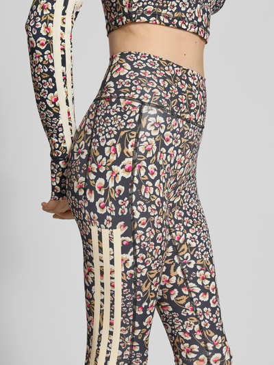 Frauenmodel trägt Slim Fit Sport-Leggings mit floralem Muster Modell 'FARM LEGGINGS' von adidas aus der adidas Sportswear Kollektion, Nahaufnahme Hüfte und Oberschenkel.