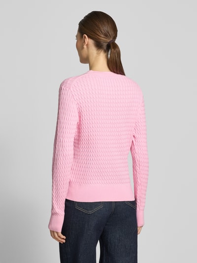 Frauenmodel trägt Slim Fit Pullover aus reiner Baumwolle von Tommy Hilfiger in Rosa mit Zopfmuster und Rundhals, Ganzkörperansicht Rückansicht.