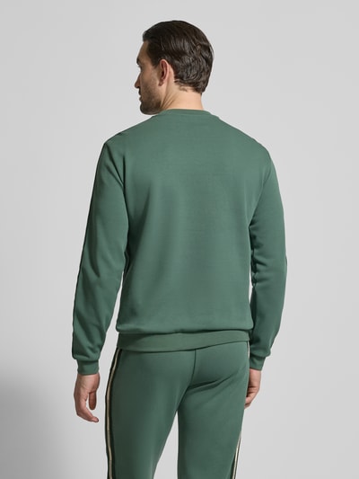Männermodel trägt Sweatshirt mit Label-Details und Rundhalsausschnitt von EA7 Emporio Armani, grün, Baumwoll-Mix, Regular-Fit, Rückenansicht, Rückenlänge bei Größe M 63 cm, Ärmellänge bei Größe M 66 cm.
