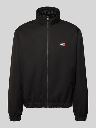 Produktfoto, Regular Fit Blouson van Tommy Jeans in look: effen zwart, met opstaande kraag, verdekte ritssluiting, labelpatch, elastische rompzoom en mouwboord, zij-steekzakken.