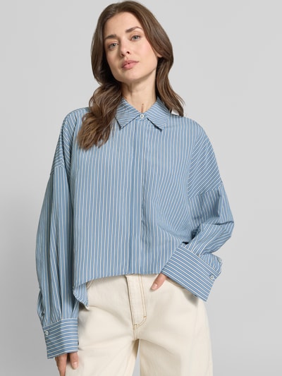 Kobieta modelka ma na sobie Relaxed Fit Bluzka z mieszanki wiskozy model 'OSHIA' od Drykorn, niebieskie paski, kołnierzyk koszulowy, zakryta listwa guzikowa, długość tyłu 59 cm, długość rękawów 65 cm, widok całej sylwetki z przodu