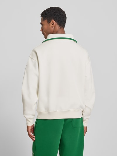 Mężczyznamodel nosi Loose Fit Troyer aus Baumwoll-Mix Model 'Tennisc' od Lacoste w kolorze kremowym i zielonym, tekstura gładka, Ganzkörperansicht Rückansicht. Kontekst: Herren troyer od Lacoste.
